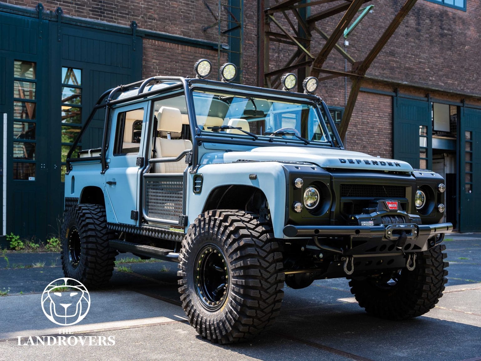 light blue bigfoot defender 110 in front of a garage door