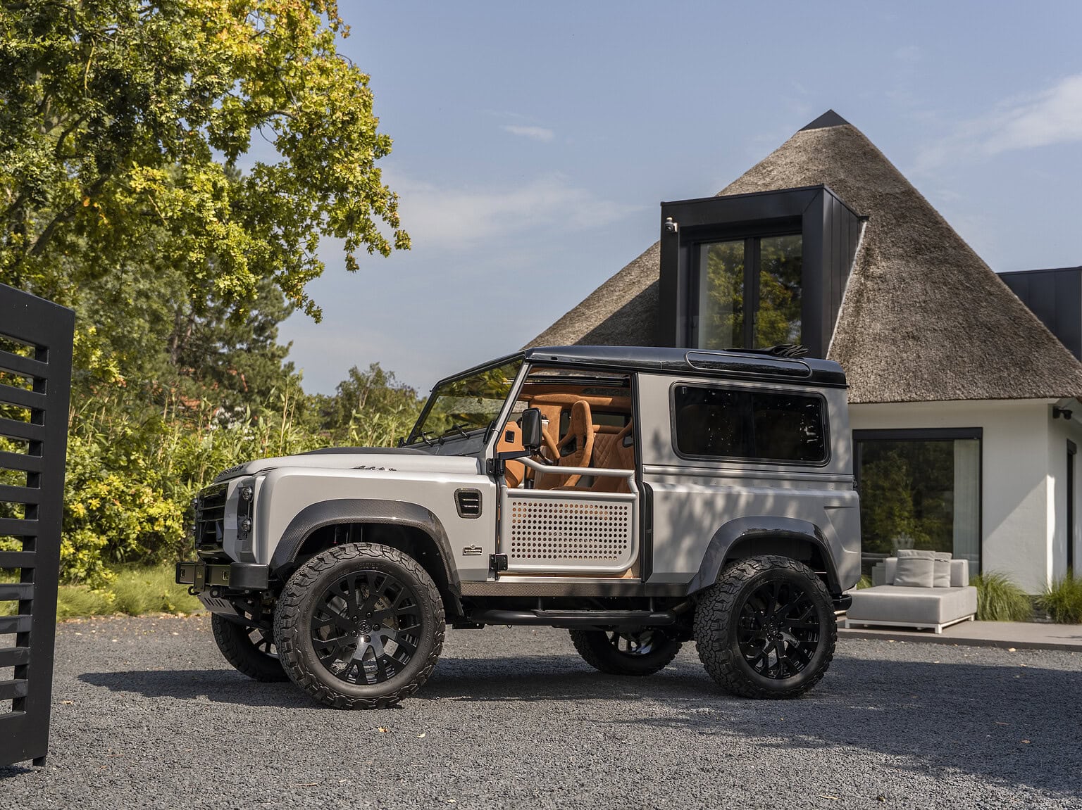 ultra bespoke Land Rover Defender 90 in silver and carbon details in front of a big house